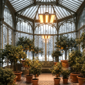 Zwei hängende Pflanzenlampen vom Modell FLORIS beleuchten und beleuchten zahlreiche Zitrusbäume in einem eleganten Jugendstil-Wintergarten, während draußen eine verschneite Winterlandschaft zu sehen ist.