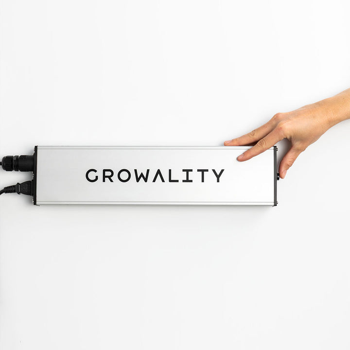 Hand hält die Smartbox der VEGA Pro LED Pflanzenlampe. Das Bild zeigt den seitlichen Taster für die manuelle Steuerung zum Dimmen und Ein-/Ausschalten.