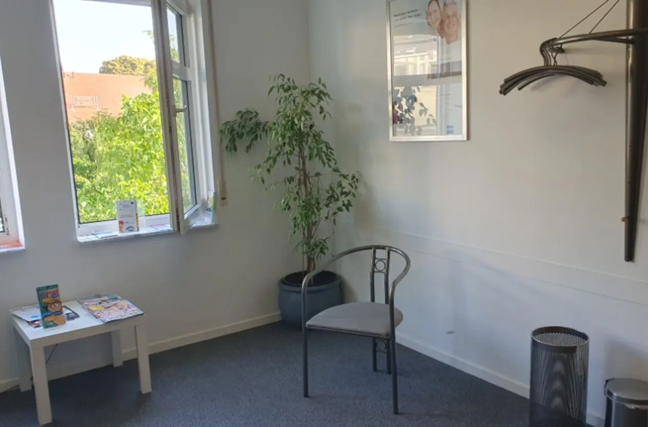 Vorher-Aufnahme: Wartezimmer einer Arztpraxis mit einer ungesunden, lichtmangelnden Zimmerpflanze in einer dunklen Raumecke ohne professionelles Pflanzenlicht.
